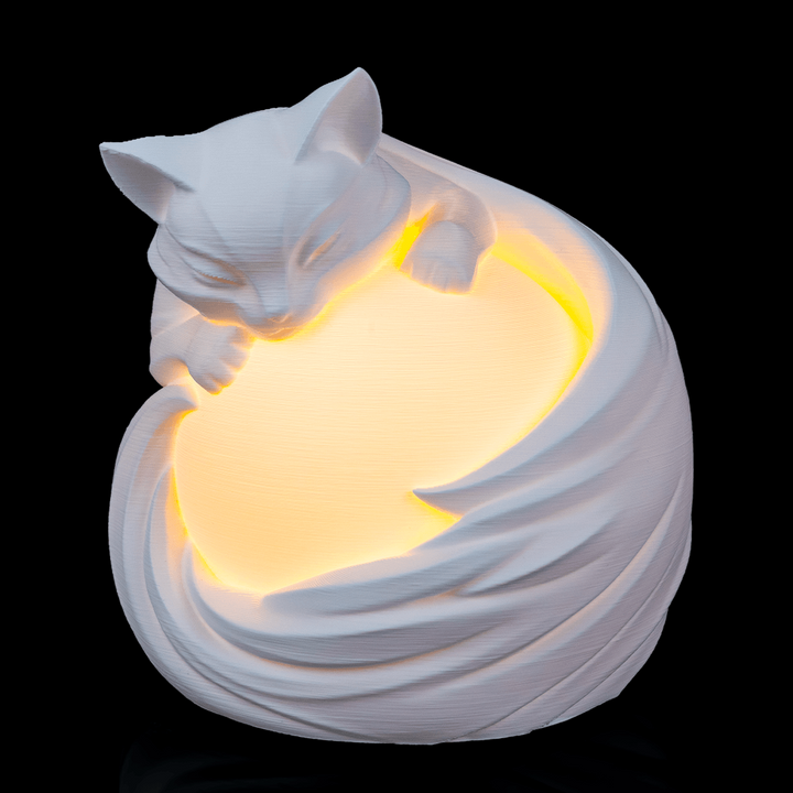 Feline Sphere Desk Lamp glowing with sculpted cat design wrapped around illuminated globe